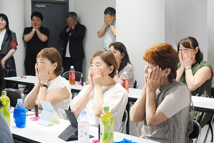 手をそえて「いまの自分の顔にありがとう」とみんなで感謝。後ろの弊社男性陣も一緒に感謝しています。